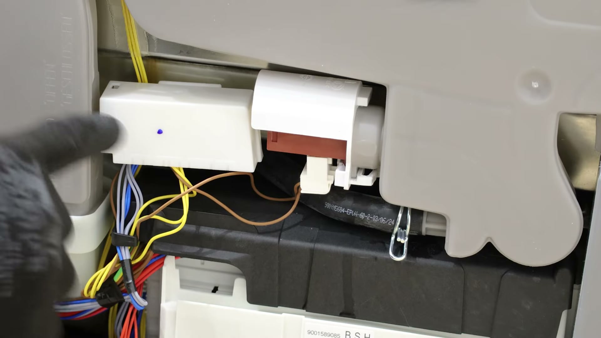 Unclipping the plastic case covering the actuator on a Bosch dishwasher