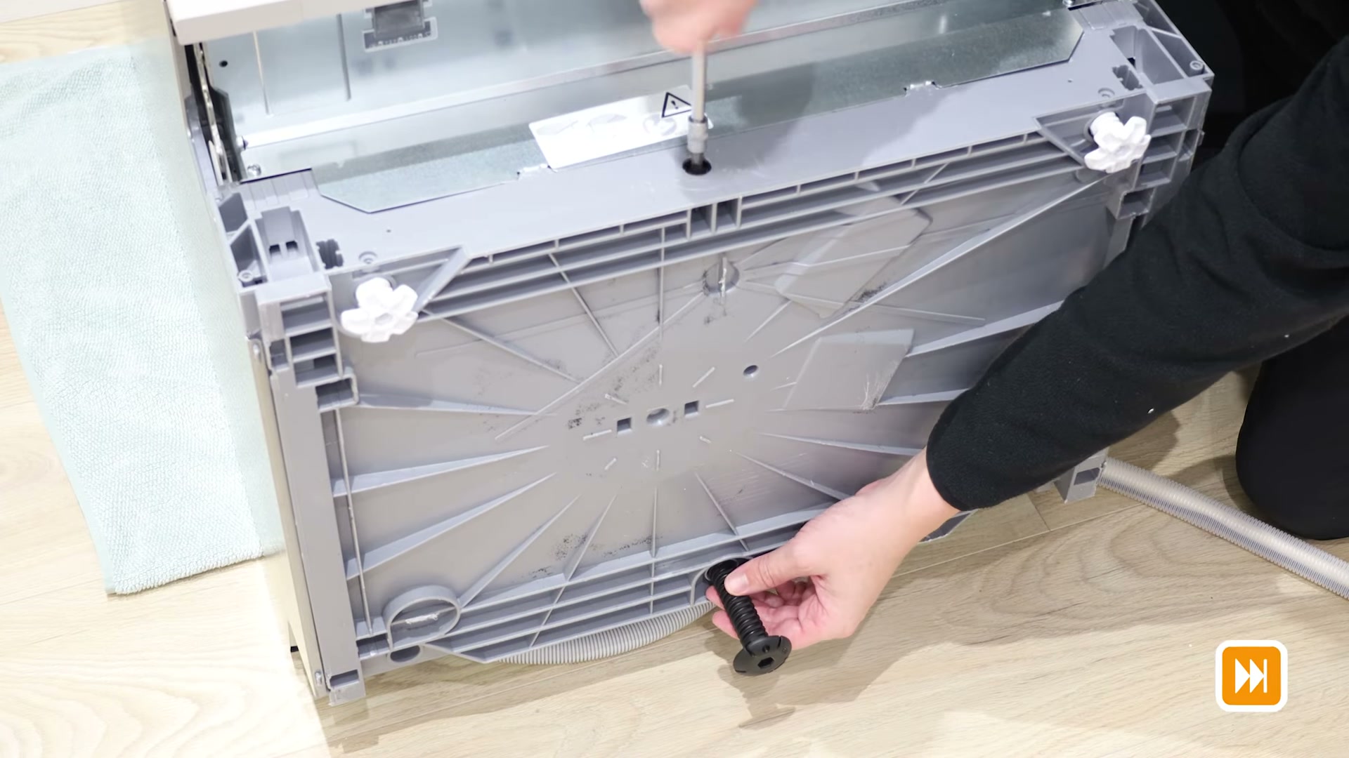 Removing the old adjustable rear foot from a Bosch dishwasher with a flathead screwdriver