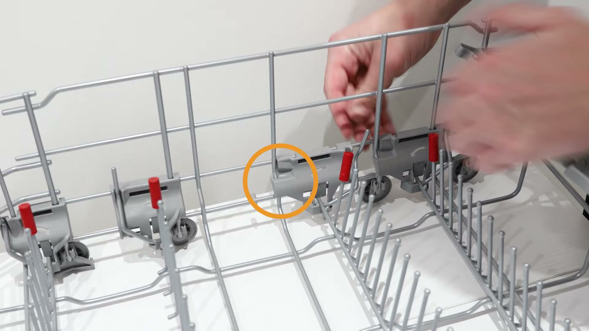 Clipping the new bearing onto the vertical metal wire of the Bosch dishwasher basket assembly