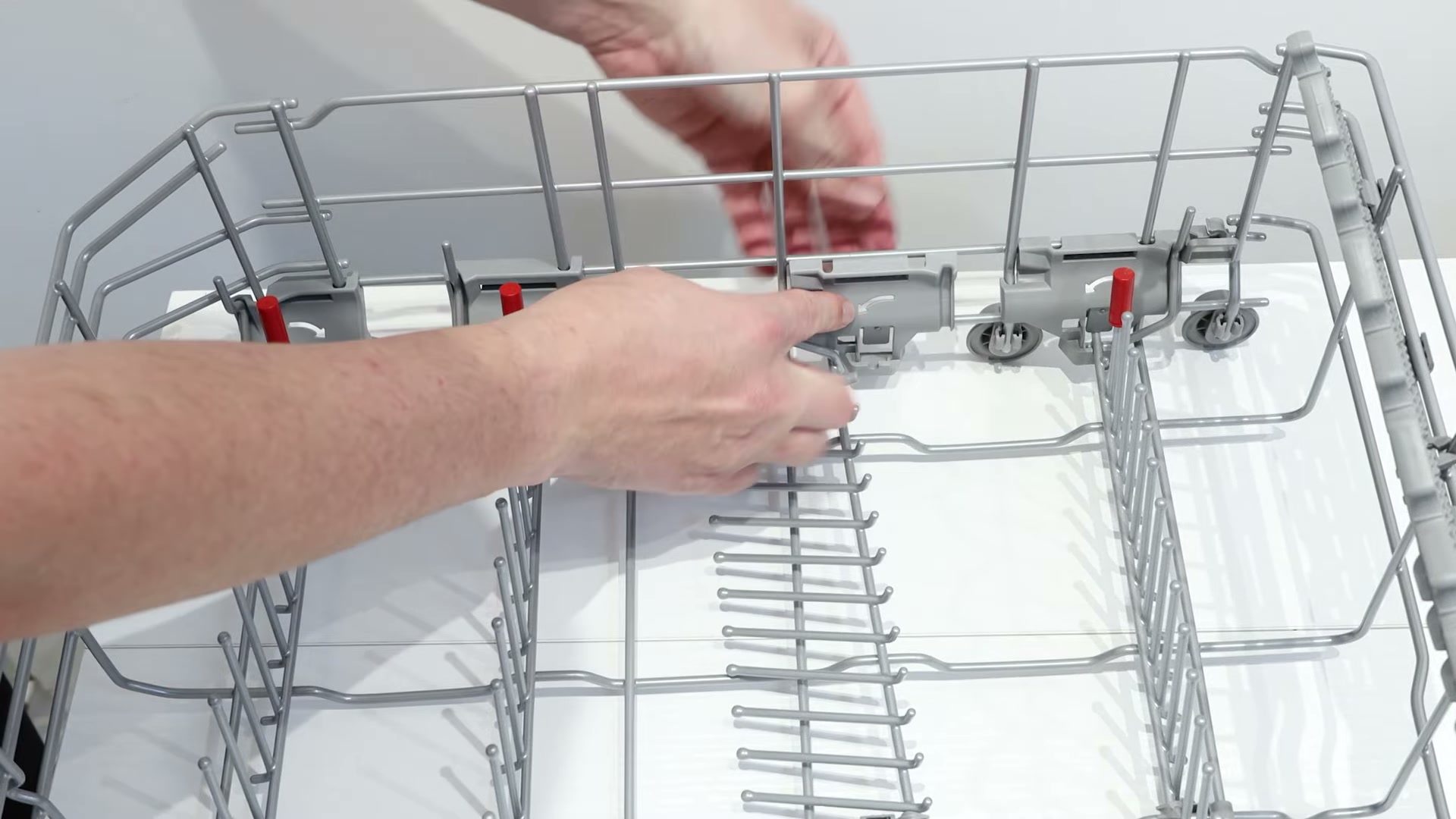Hands unclipping the old bearing from a Bosch dishwasher basket assembly