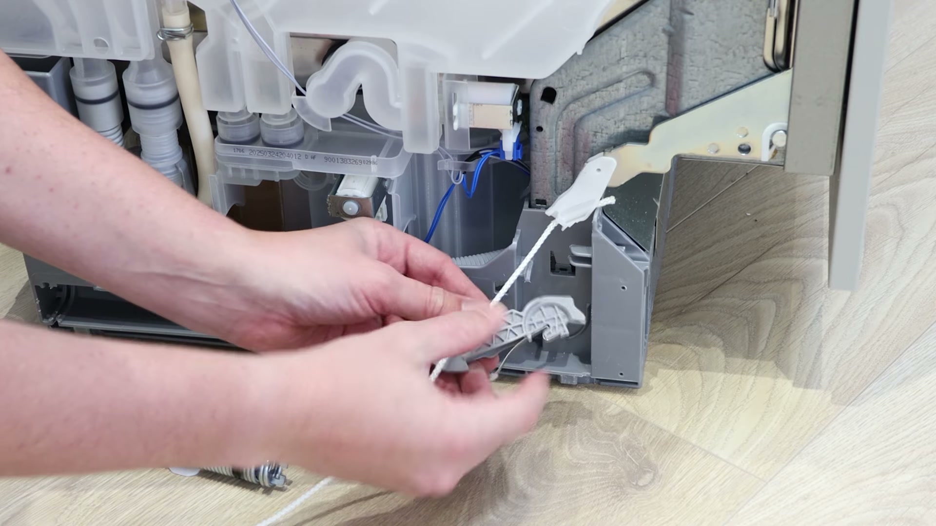 Threading the new door hinge rope string through the cable guide on a Bosch dishwasher