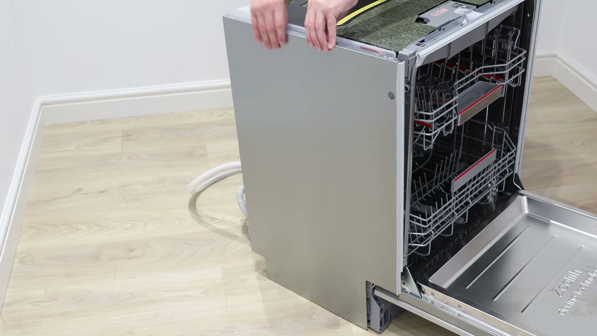 Removing the side panel from a Bosch dishwasher to access the door hinge rope string