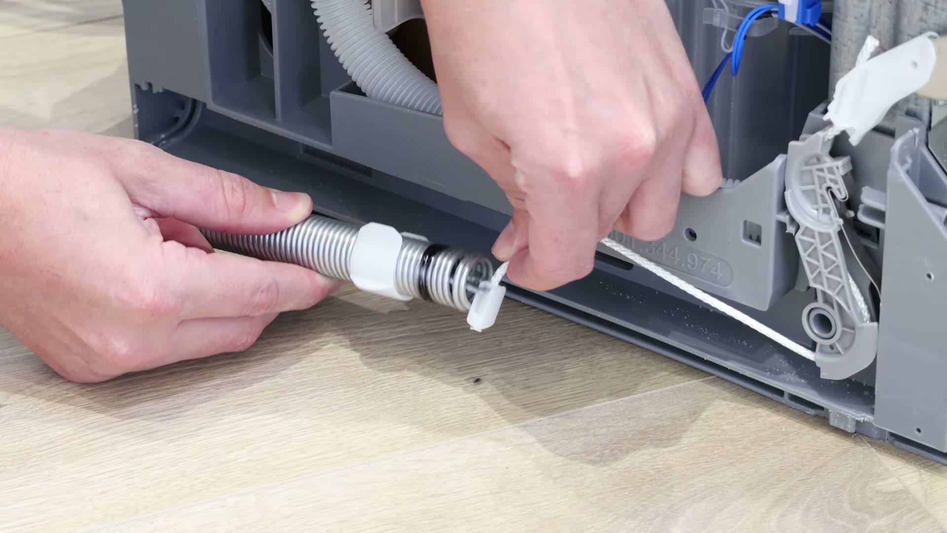 Detaching the old rope string from the door hinge spring on a Bosch dishwasher