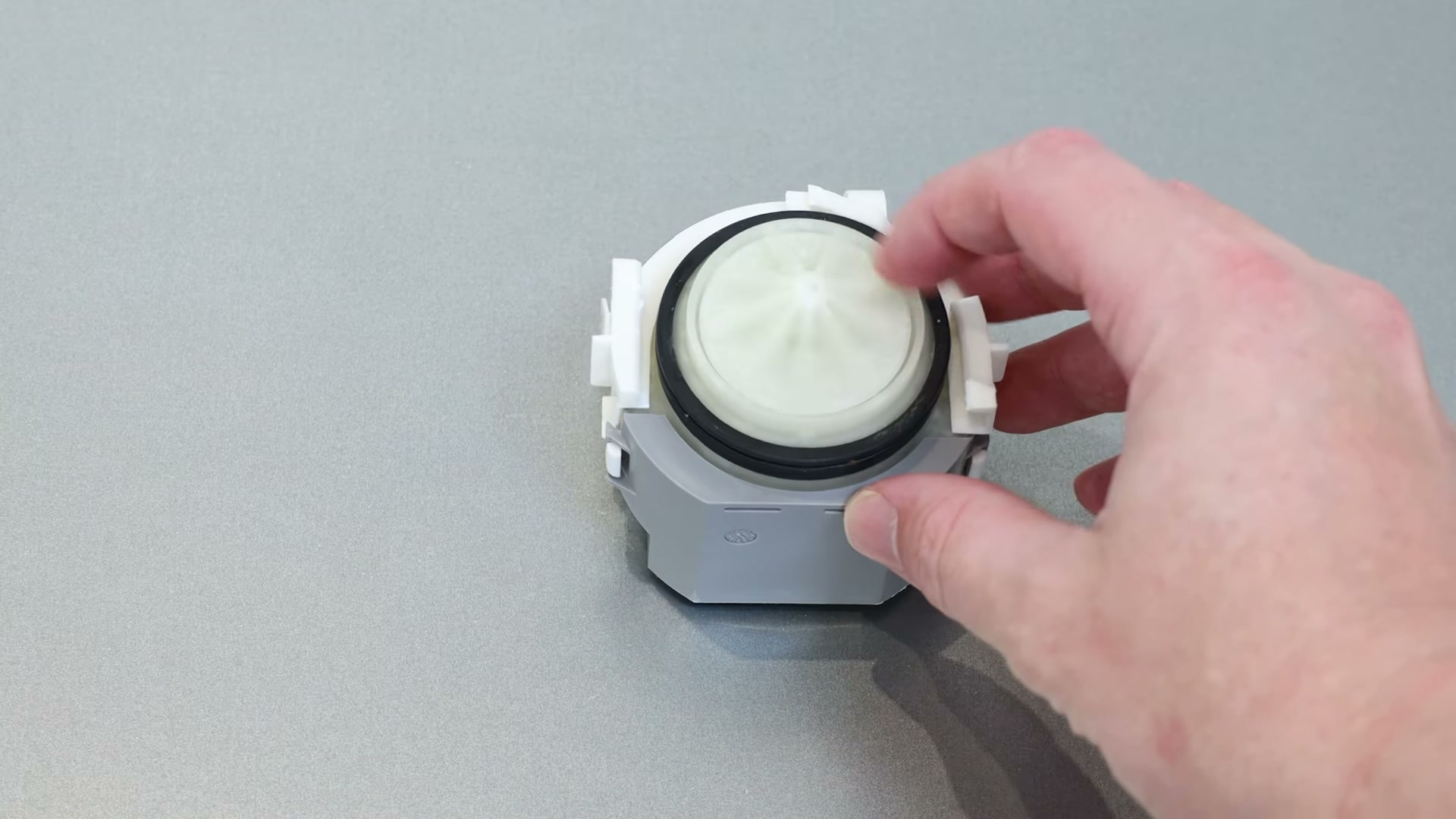 New Bosch dishwasher drain pump held in hand, showing the locking tabs and impeller