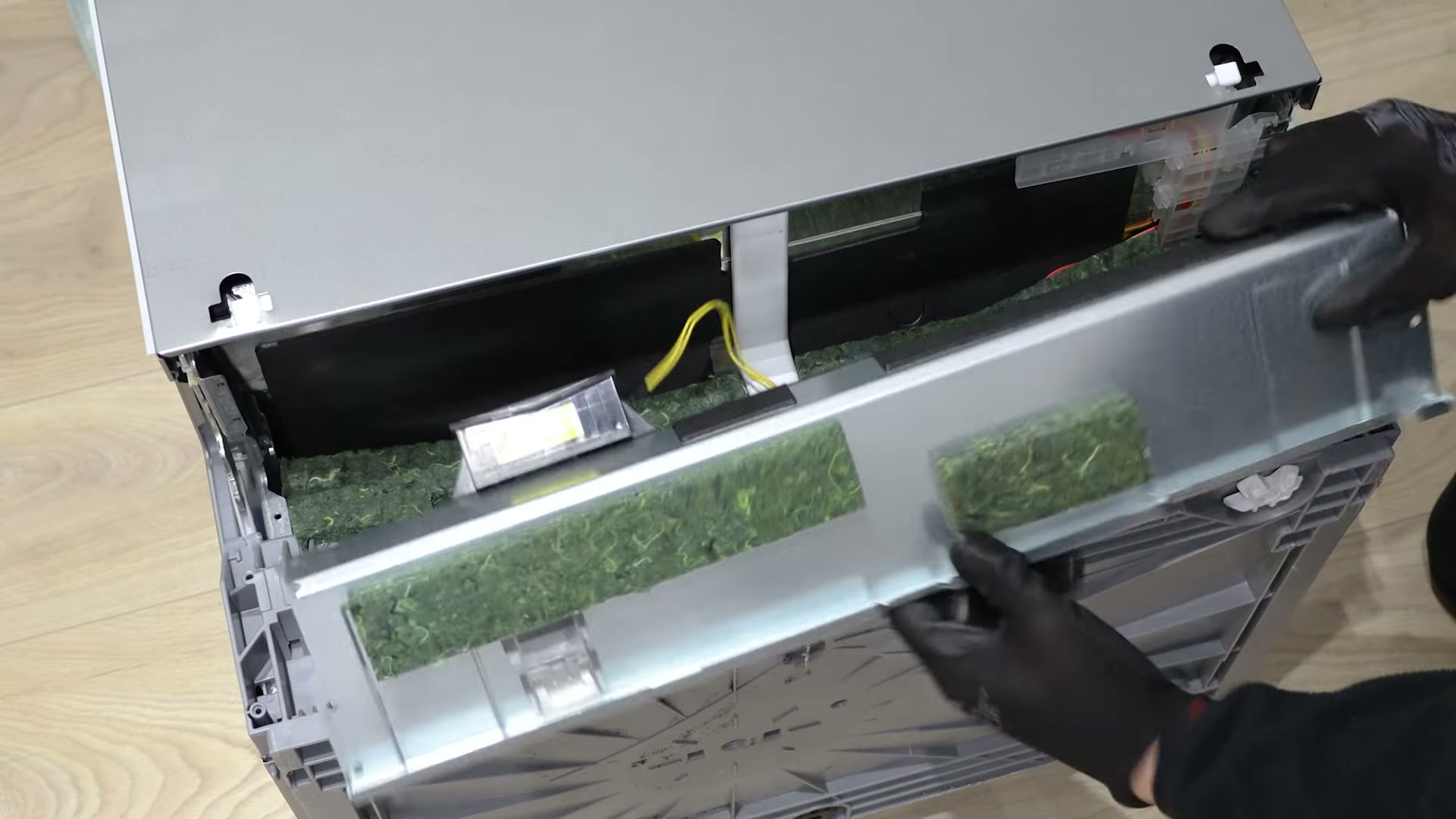 Foam insulation panel being lifted away from the base of a Bosch dishwasher to expose the drain pump