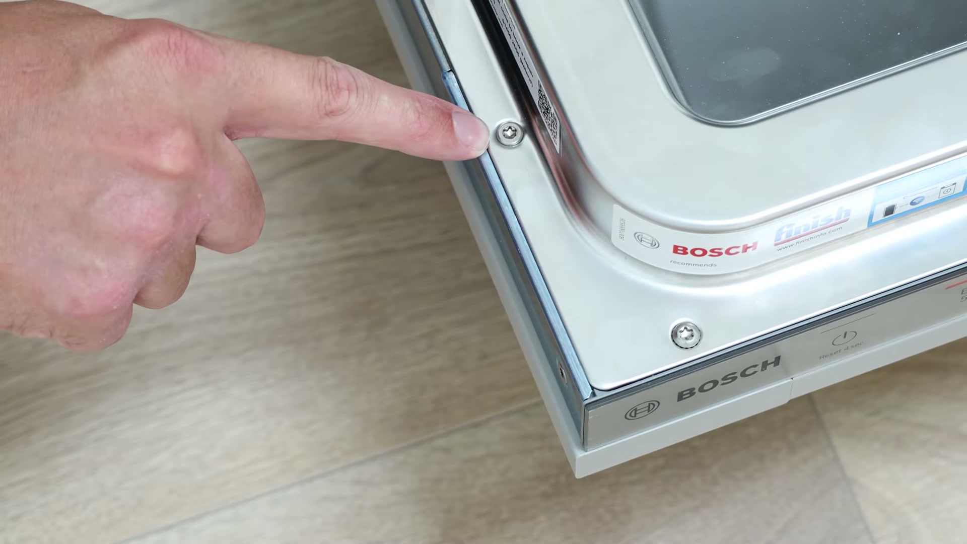 Pointing to the T20 Torx screws on a Bosch integrated dishwasher cabinet door