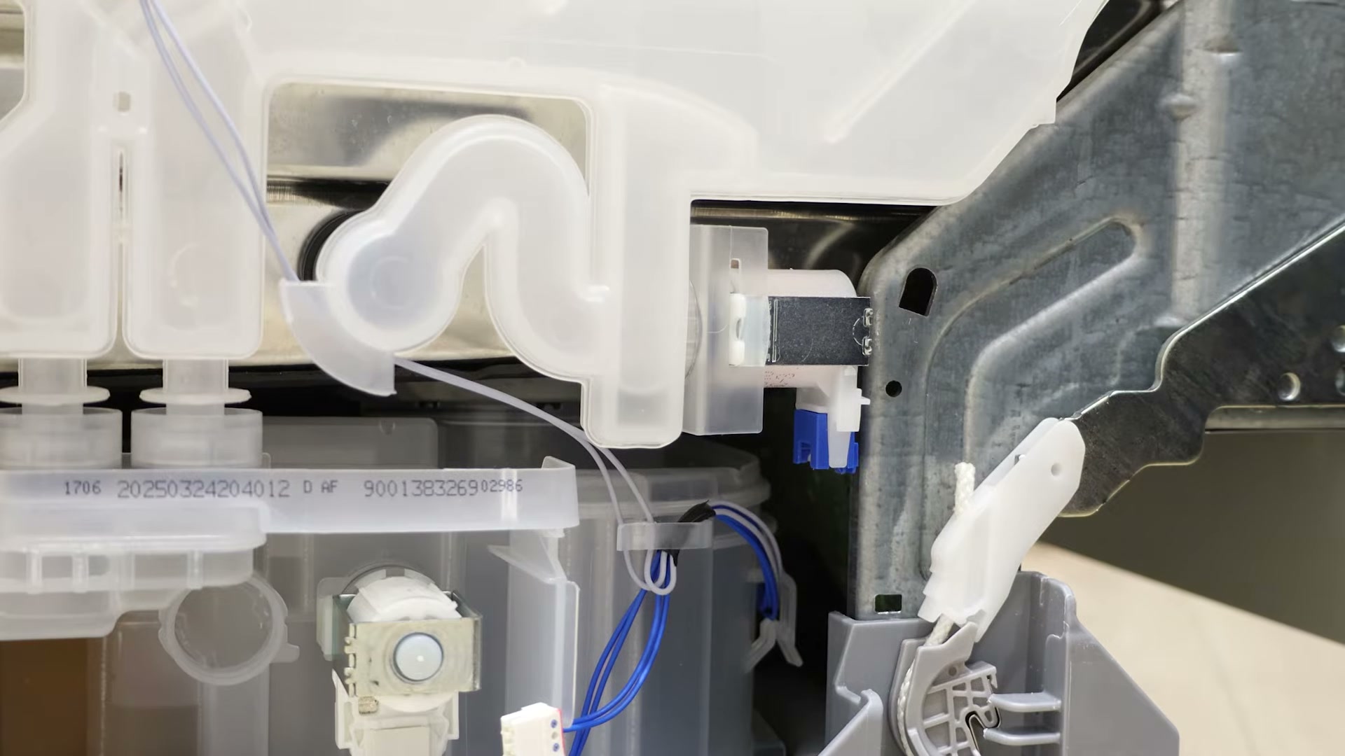 Clear plastic heat exchanger and outlet valve visible on the side of a Bosch dishwasher