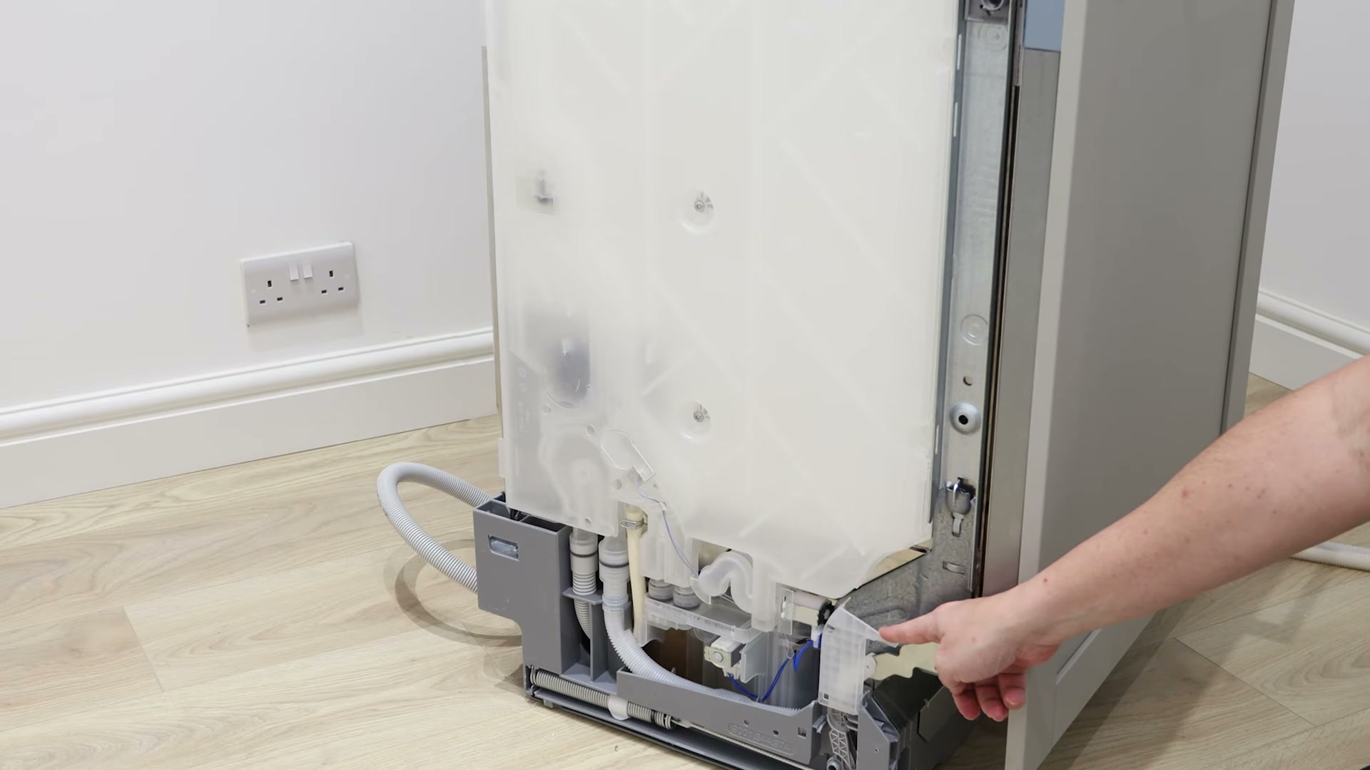 Pointing at the heat exchanger outlet valve location next to the hinge on a Bosch dishwasher