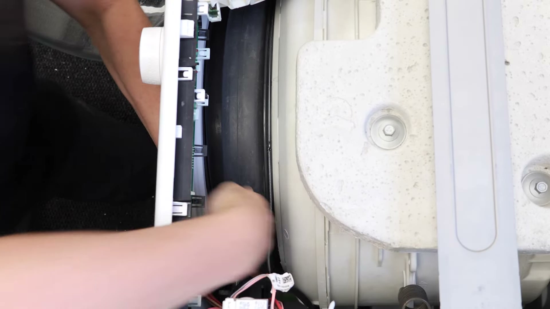 Door seal retaining spring being fed around the drum of a Hotpoint washing machine