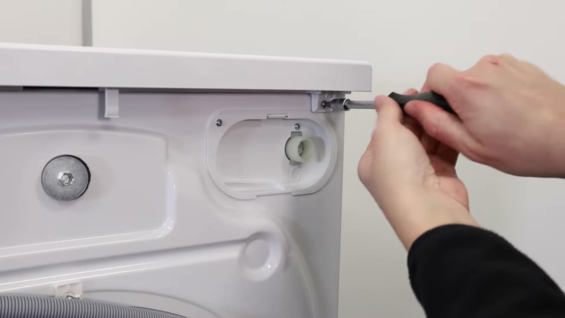 Flat-head screwdriver refitting the top lid screw on a Hotpoint washing machine