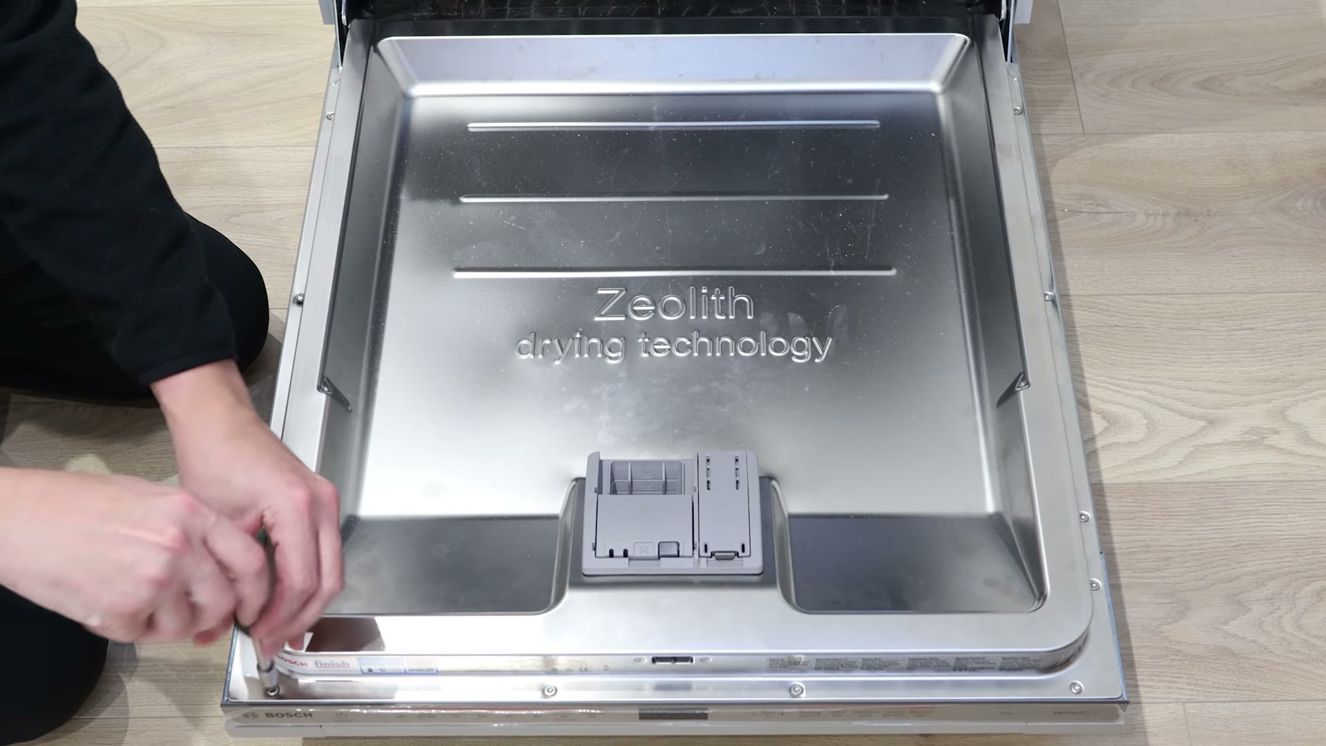 Unscrewing the T20 Torx screws holding the integrated cabinet door on a Bosch dishwasher