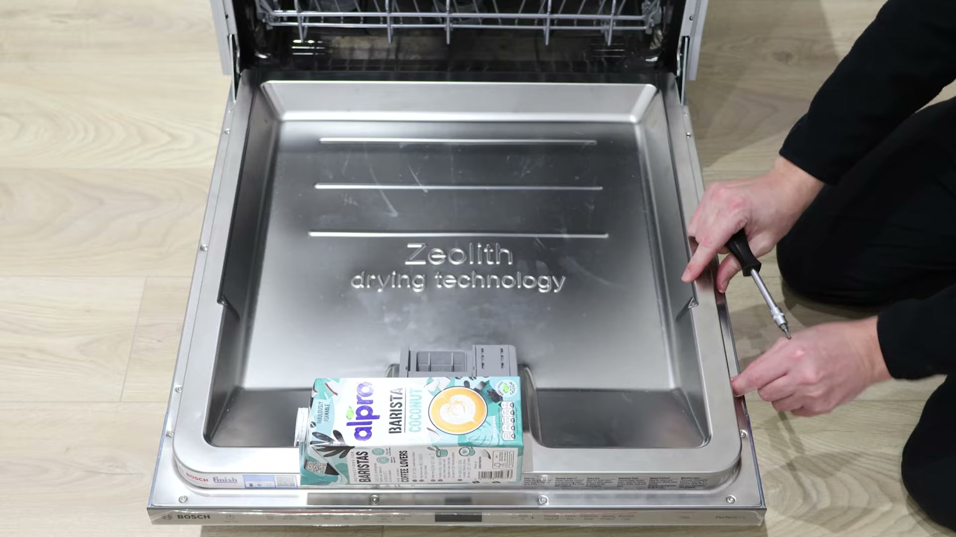Milk carton weighing down a Bosch dishwasher door while removing the outer front panel screws