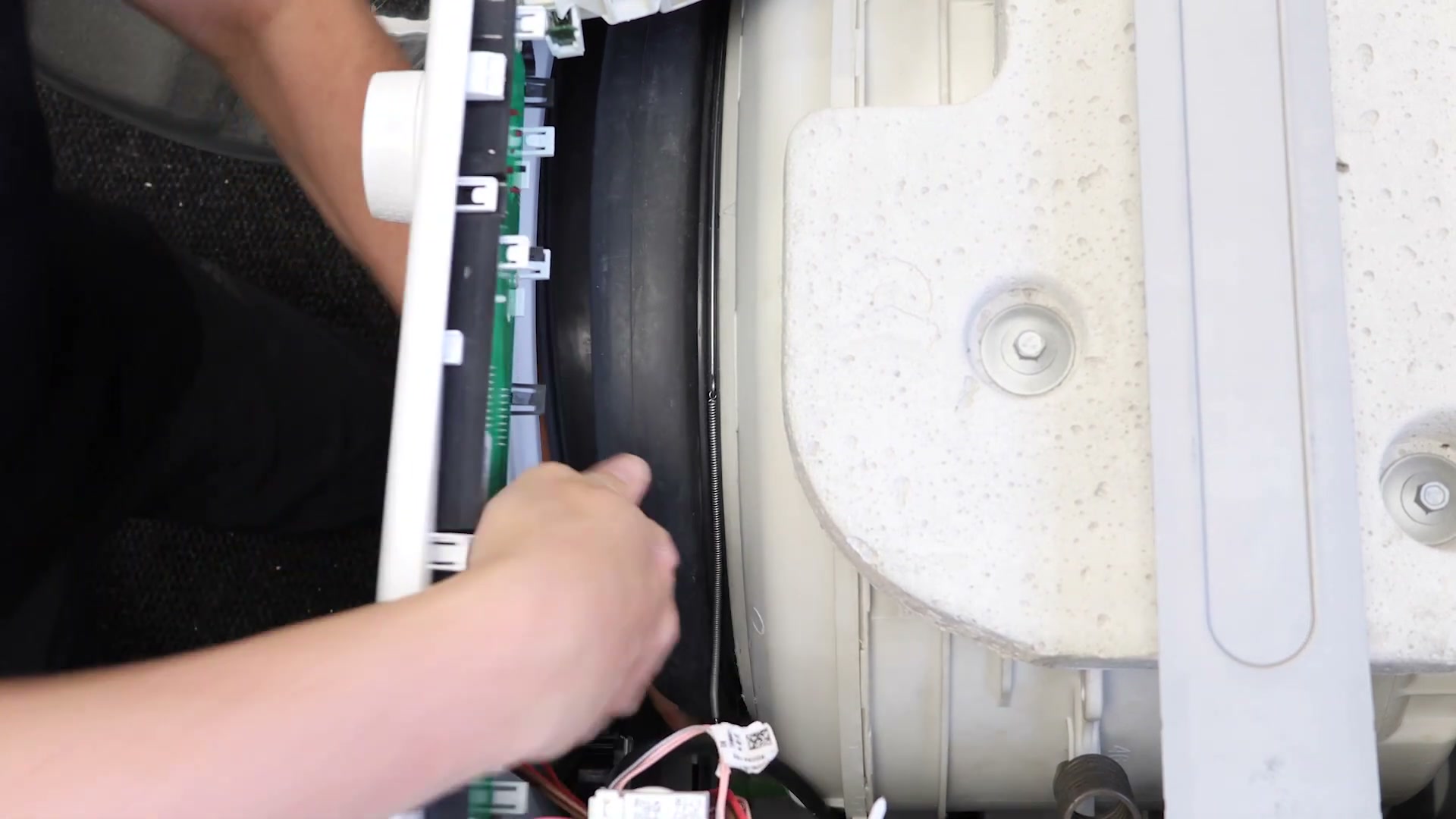 New door seal retaining spring band being fed into place around the Hotpoint washing machine door seal